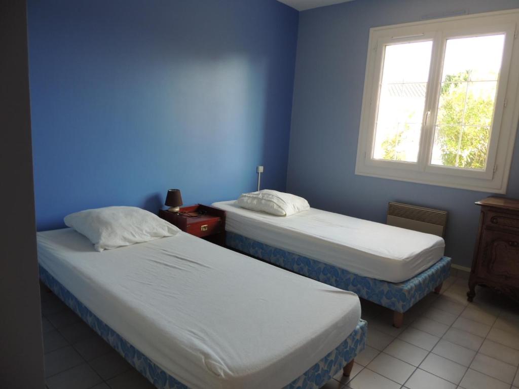 two beds in a room with blue walls and a window at Maison Les Sables-d&#39;Olonne, 4 pièces, 6 personnes - FR-1-92-798 in Les Sables-d&#39;Olonne
