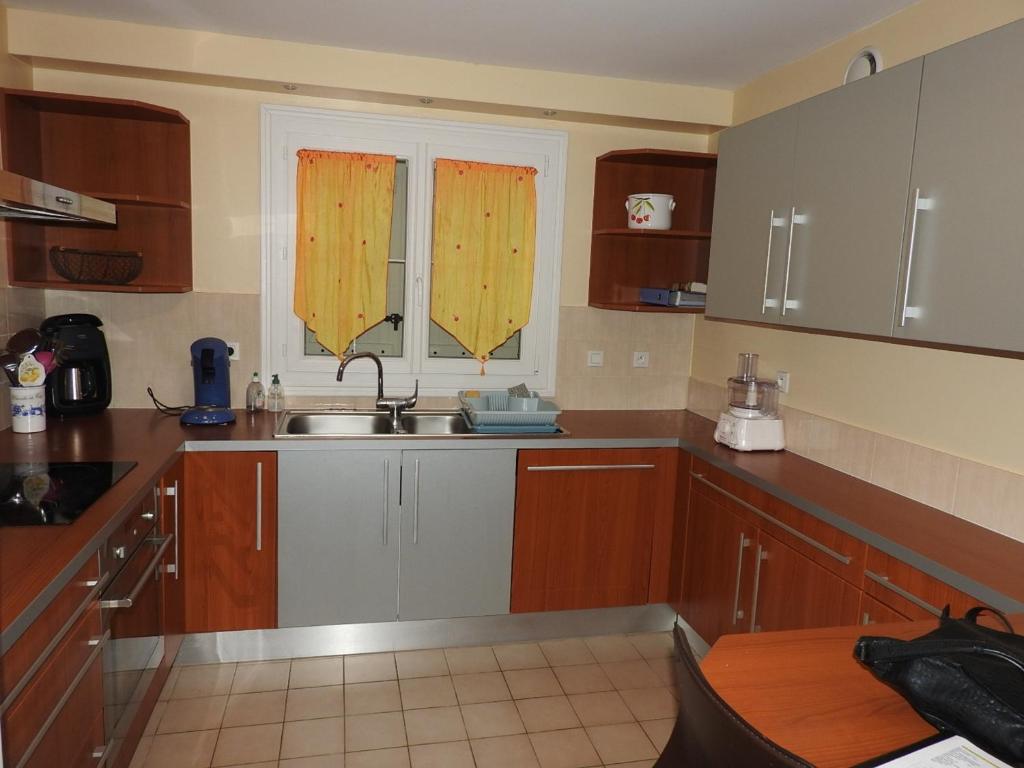 a kitchen with wooden cabinets and a sink and two windows at Maison Les Sables-d&#39;Olonne, 4 pièces, 6 personnes - FR-1-92-798 in Les Sables-d&#39;Olonne
