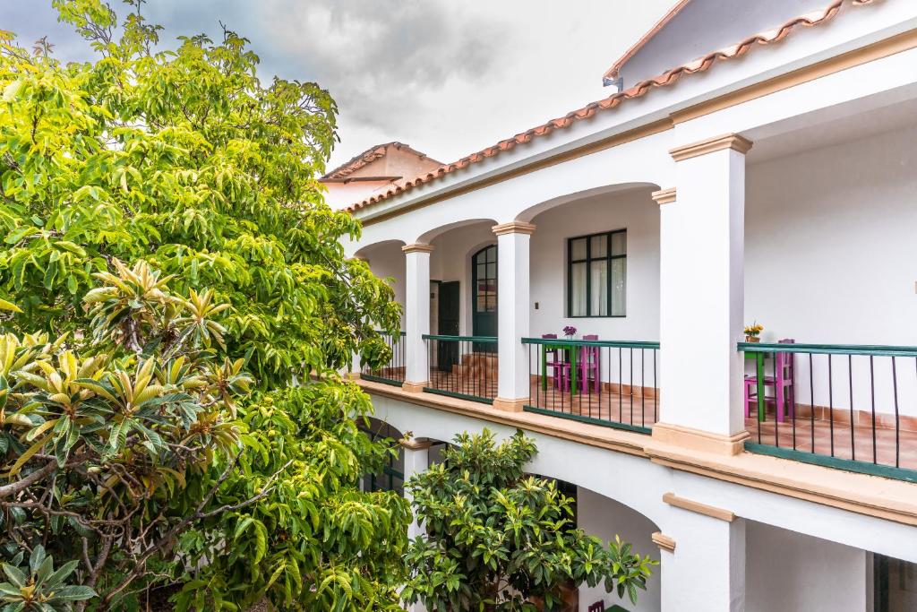 Casa blanca con balcones y árboles en Dragonfly Guest House en Sucre