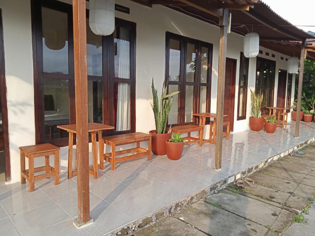 a porch with wooden benches and potted plants at Rosella Cottages - Homestay - Yogyakarta in Yogyakarta