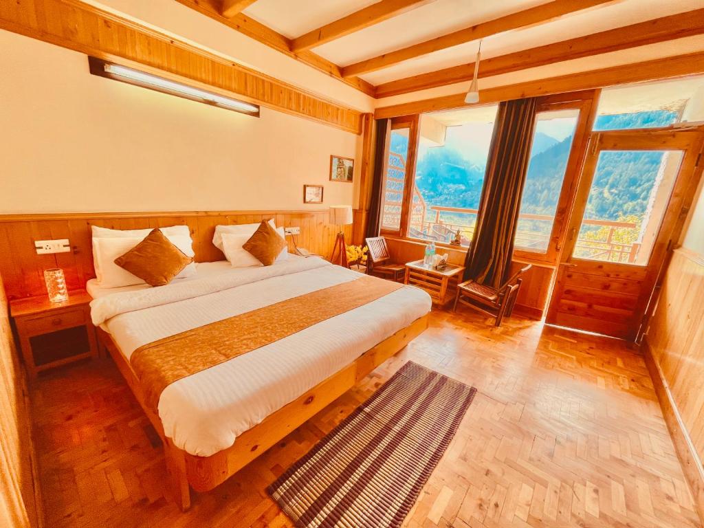 a bedroom with a bed in a room with windows at Valley of god in Manāli