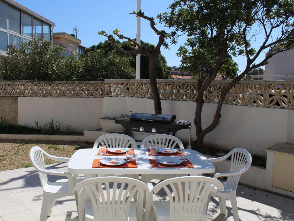 - une table blanche avec des chaises et un grill dans l'arrière-cour dans l'établissement Maison familiale rénovée, à 100m de la plage, terrasse, garage, wifi, au centre de Port-la-Nouvelle - FR-1-229C-51, à Port-la-Nouvelle