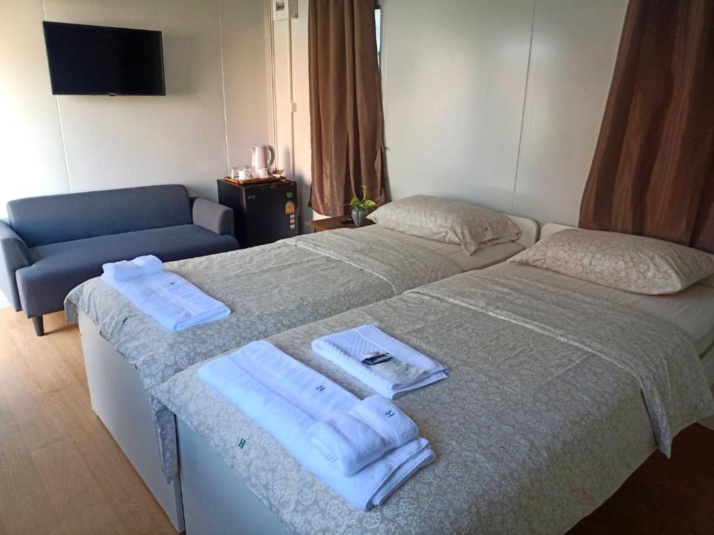 2 Betten in einem Hotelzimmer mit Handtüchern darauf in der Unterkunft Homey Hut Ayutthaya in Phra Nakhon Si Ayutthaya