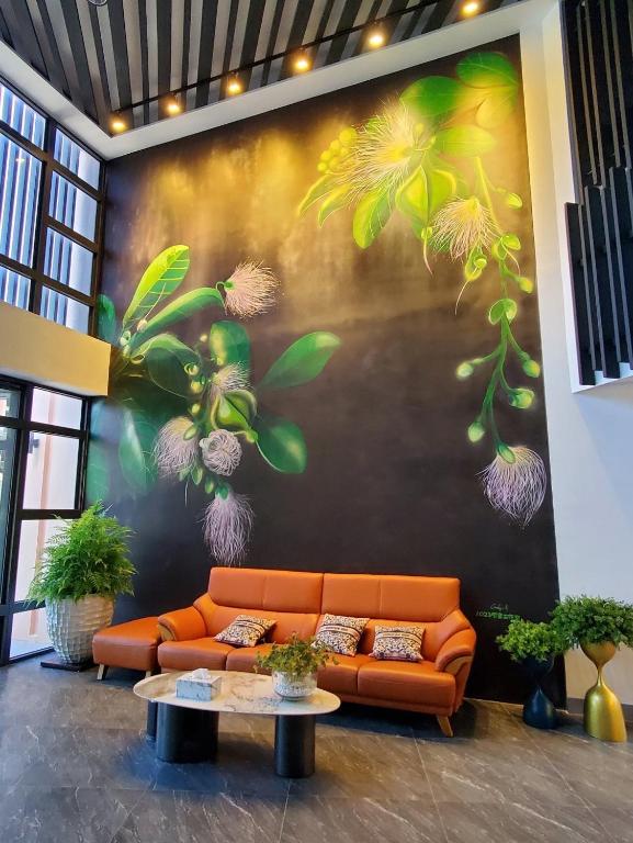 un divano arancione in una stanza con un dipinto sul muro di Shange Beach Club Homeatay a Città Vecchia di Hengchun
