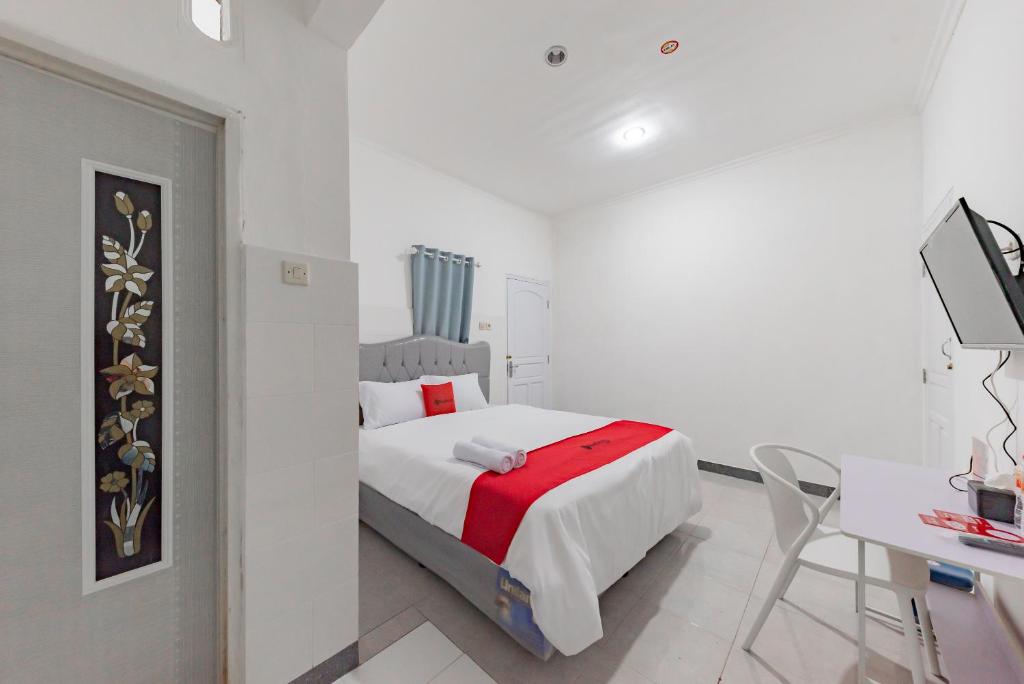 een witte slaapkamer met een bed en een bureau bij RedDoorz Syariah near Alun Alun Ciledug Cirebon in Cirebon