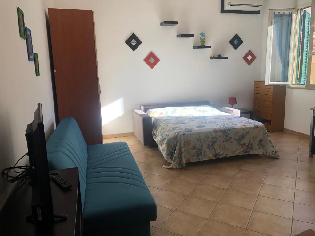 a bedroom with a bed and a couch and a tv at Liana monolocale in San Vincenzo