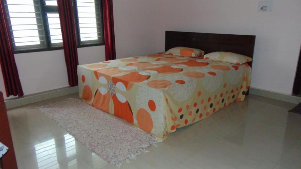 an orange and white bed in a room with windows at Shree Raksha Homestay in Gonikoppal
