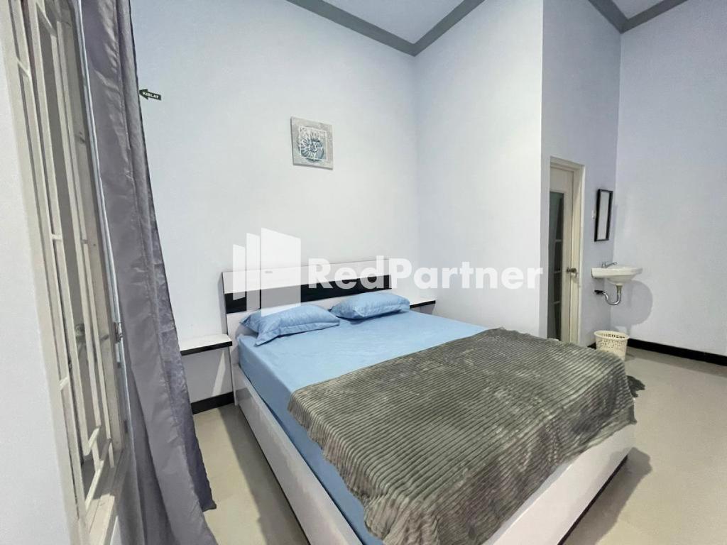 1 dormitorio con 1 cama en una habitación blanca en N3 Syariah near Stasiun Tegal Mitra RedDoorz en Tegal