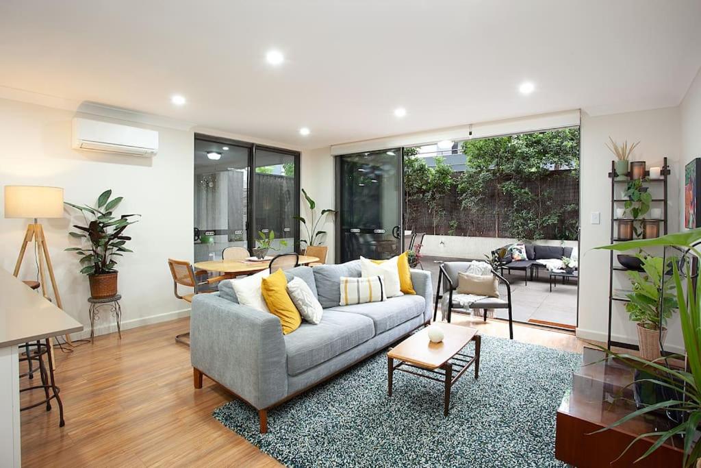 uma sala de estar com um sofá e uma mesa em Huge 3 Bed Camperdown Garden Apt w Parking Aircon em Sydney
