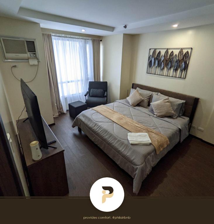 a bedroom with a bed and a television and a chair at SPACIOUS 1BR NEAR SOLAIRE & SM MOA in Manila