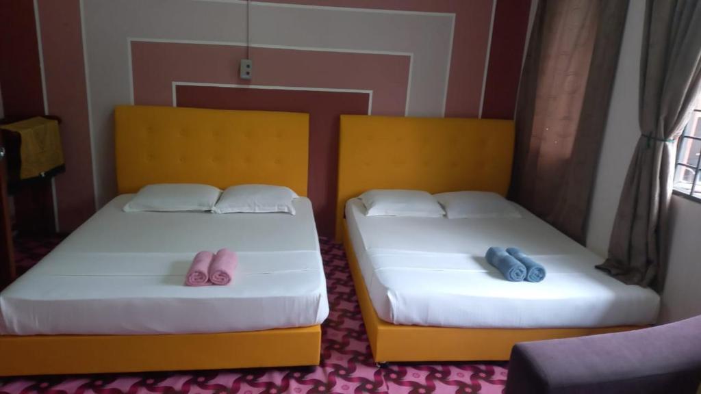 two beds with pink and blue slippers on them at 7Rooms Hotel Budget in Bandar  Pusat Jengka