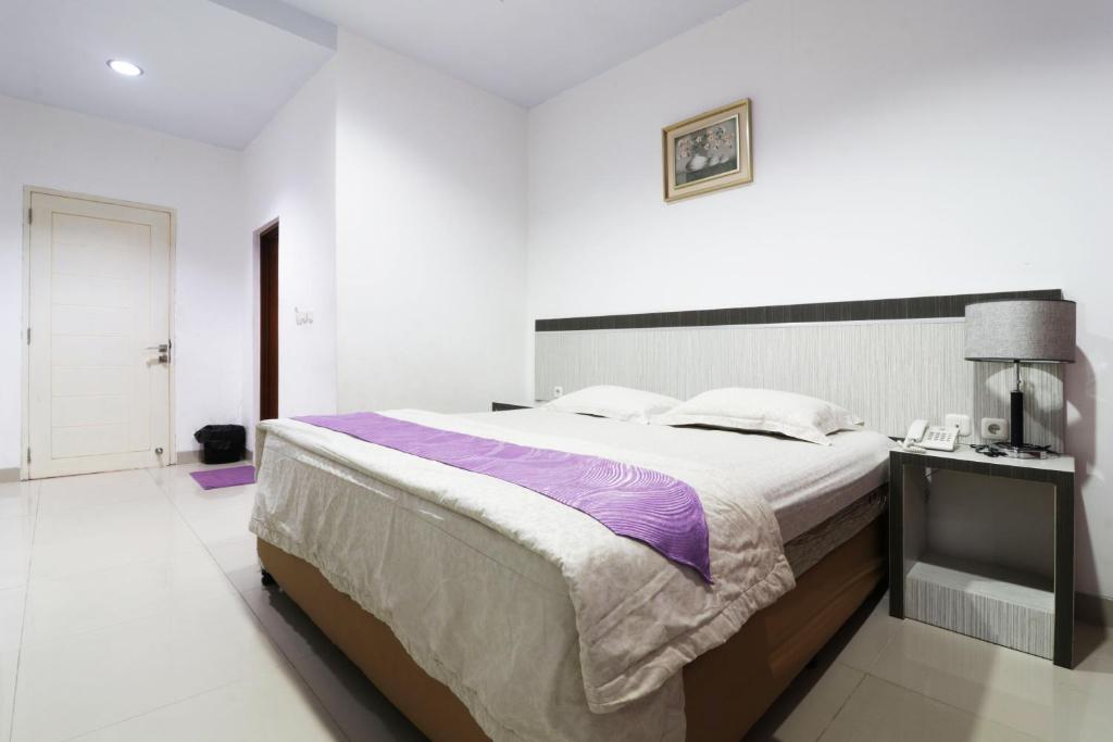 a bedroom with a large bed in a white room at Paus Guest House Pekanbaru in Pekanbaru