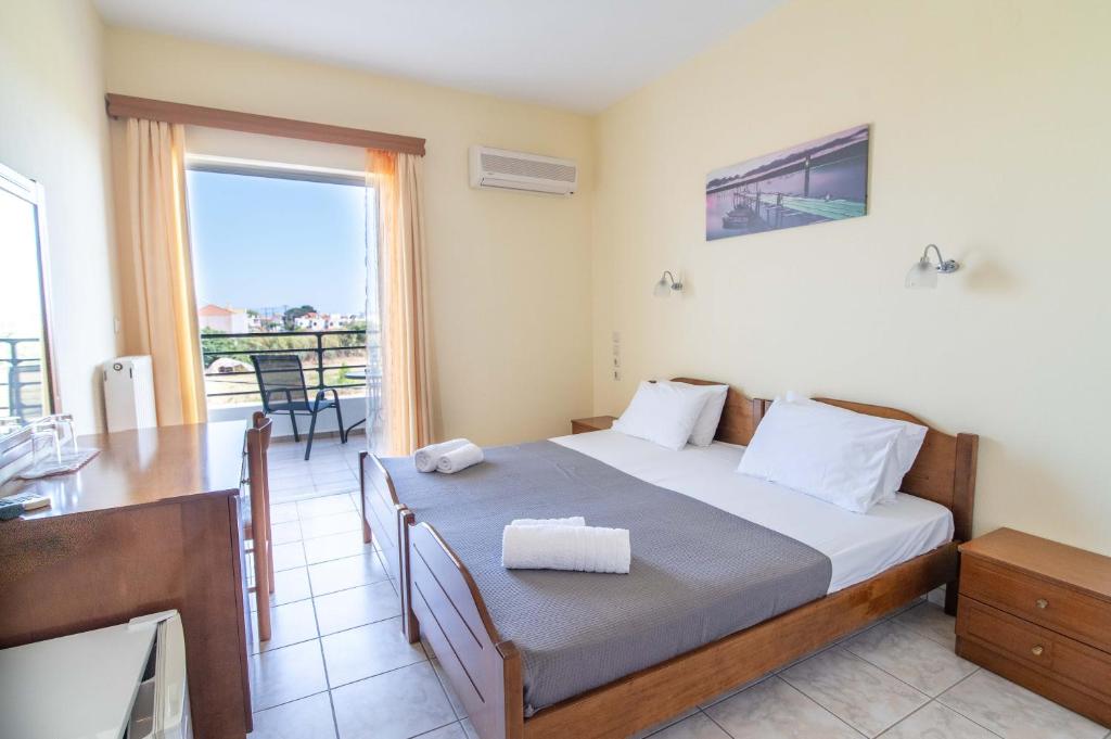 Schlafzimmer mit einem Bett, einem Tisch und einem Fenster in der Unterkunft Iraklis Hotel in Mitikas