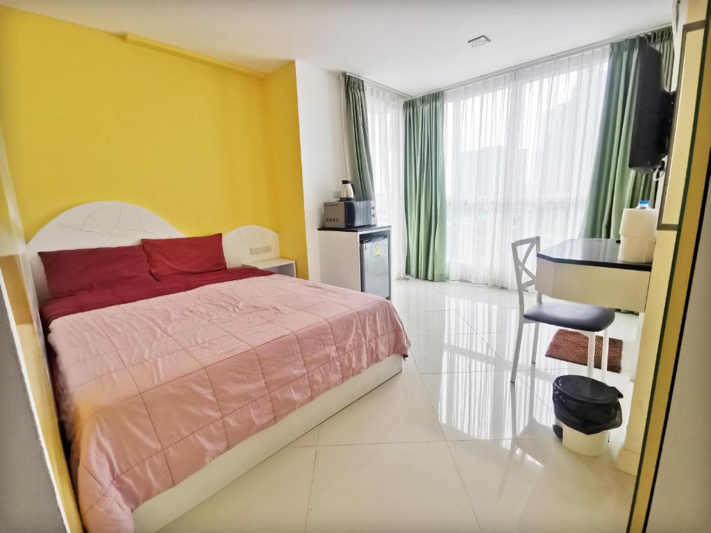 - une chambre avec un lit et un mur jaune dans l'établissement Daisy Residence, à Jomtien Beach