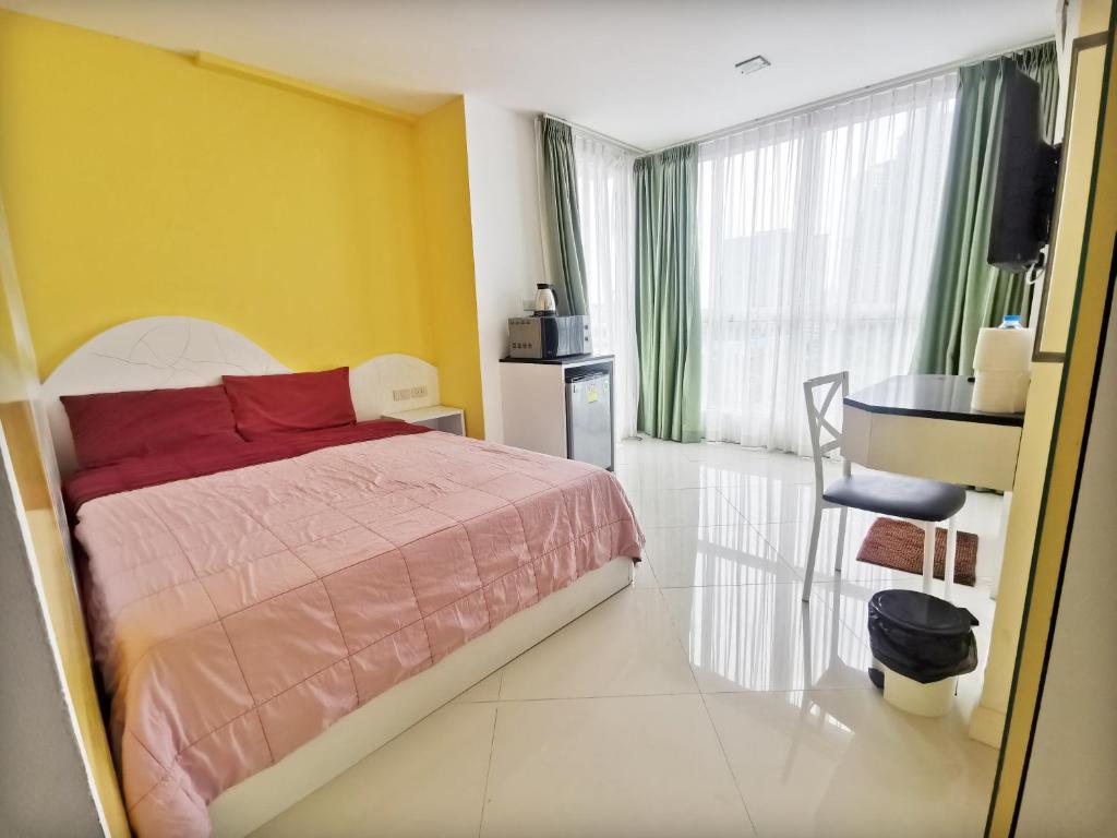 een slaapkamer met een bed en een gele muur bij Daisy Residence in Jomtien Beach