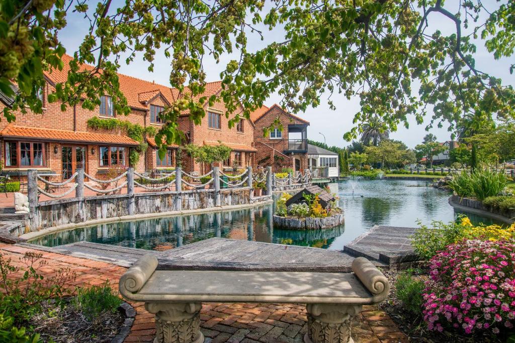 een bankje naast een rivier met huizen bij Compass Cottage - Monaco Resort in Nelson