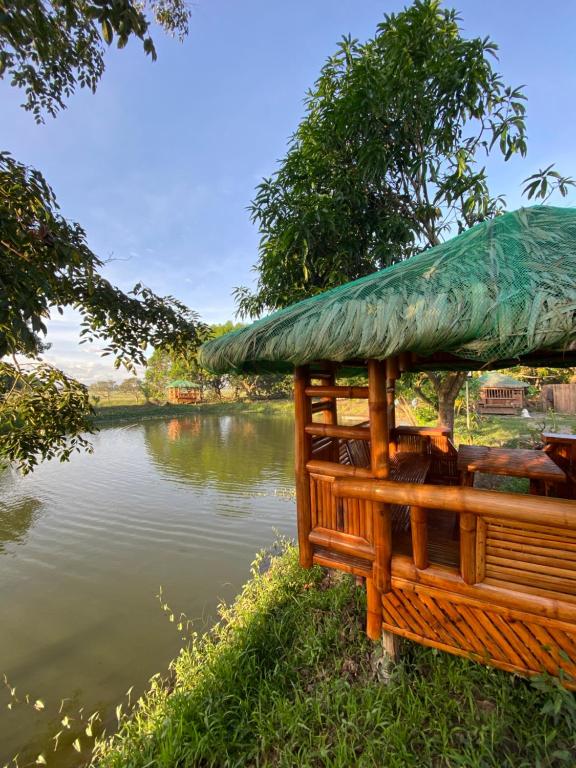 pawilon z dachem trawy obok rzeki w obiekcie Balai Consuelo Pamingwitan Campground w mieście Buliran