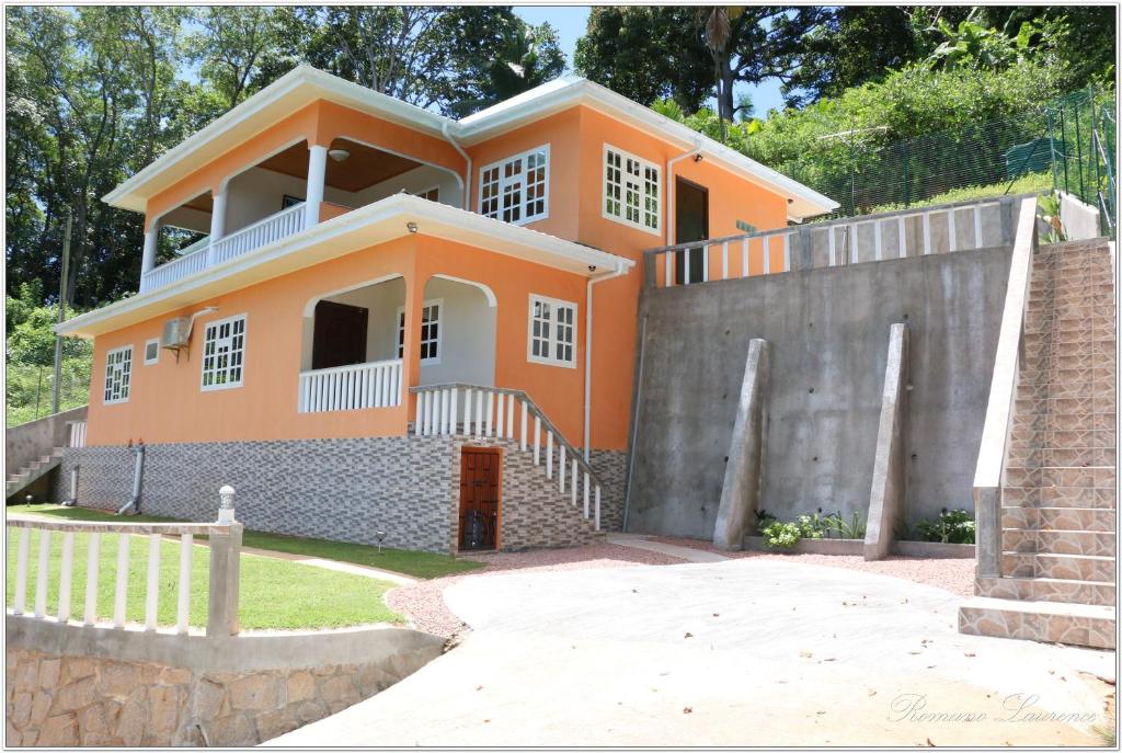 una casa naranja con una valla delante de ella en Exotic Guest House en Praslin