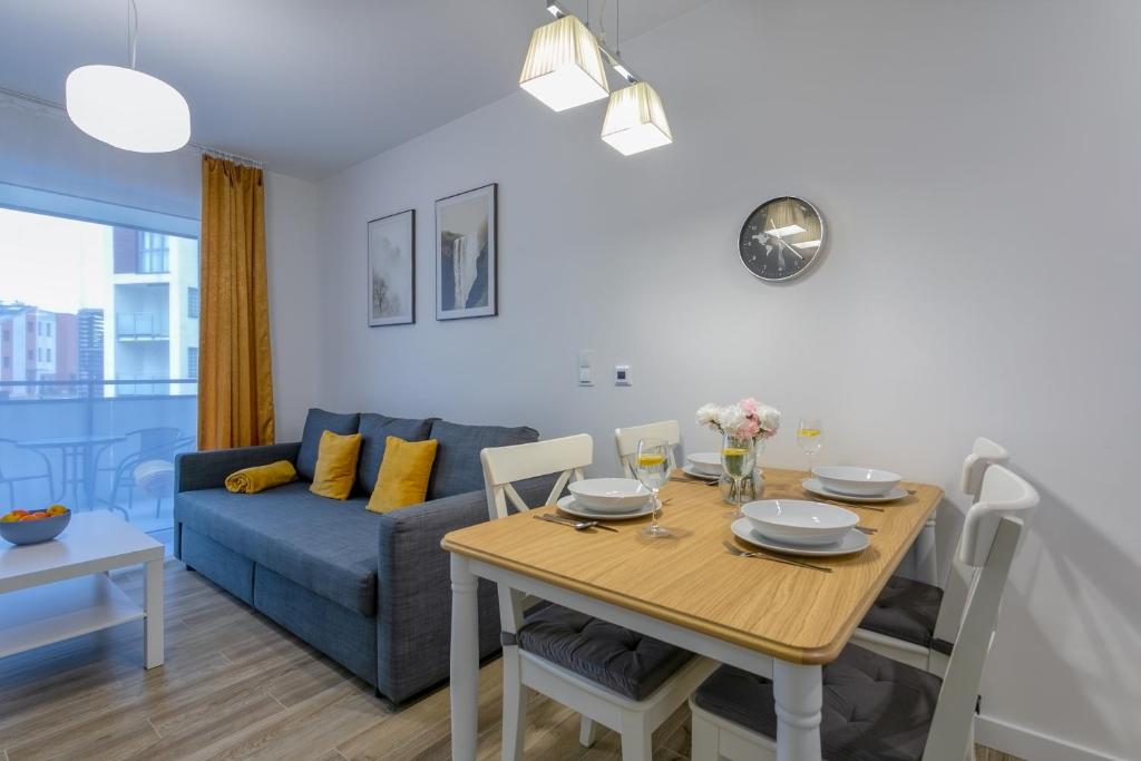 uma sala de estar com uma mesa e um sofá azul em Apartament Bryza Jantar by TriApart em Jantar