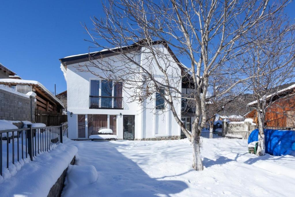 ein weißes Haus mit einem Baum im Schnee in der Unterkunft sweet dreams bakuriani in Bakuriani