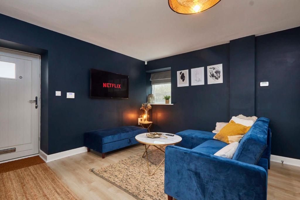 a living room with blue walls and a blue couch at Homebird Property - Mill Cottage in Leeds