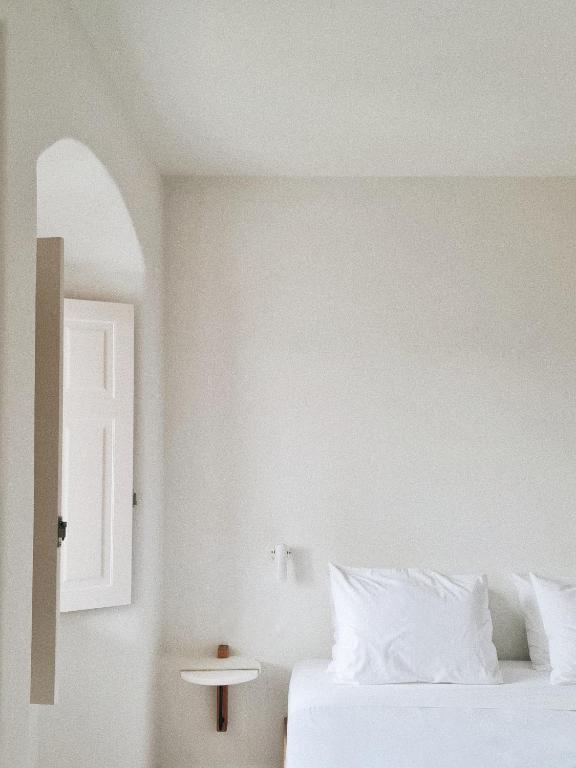 a white bedroom with a bed and a window at Ammothines Cycladic Suites in Naxos Chora