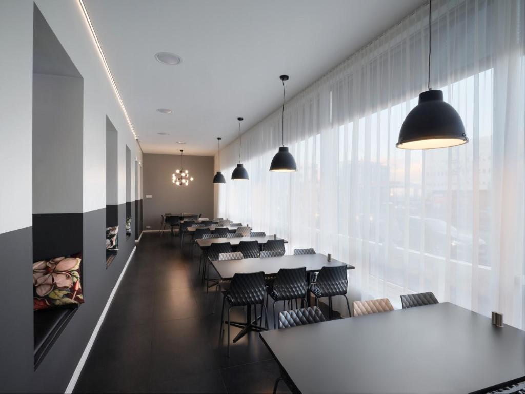 a row of tables and chairs in a room with windows at Hotel Cabin in Reykjavík