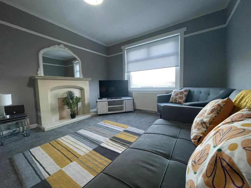 uma sala de estar com um sofá e uma lareira em Raploch House em Larkhall