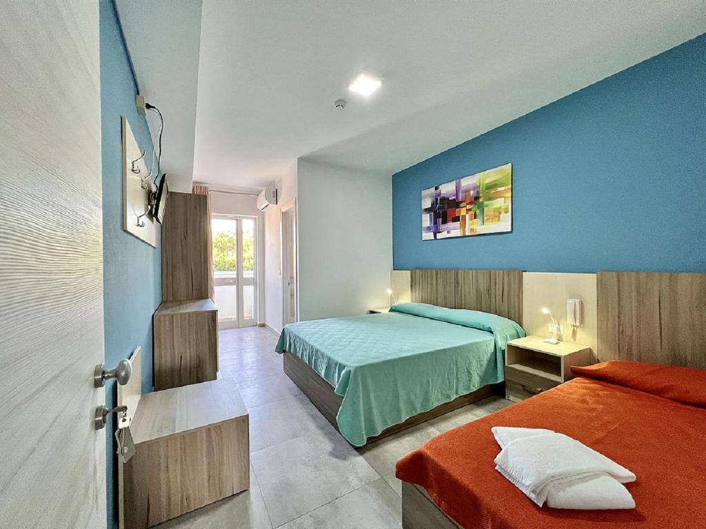 una camera con due letti e una parete blu di Hotel Old River a Lignano Sabbiadoro