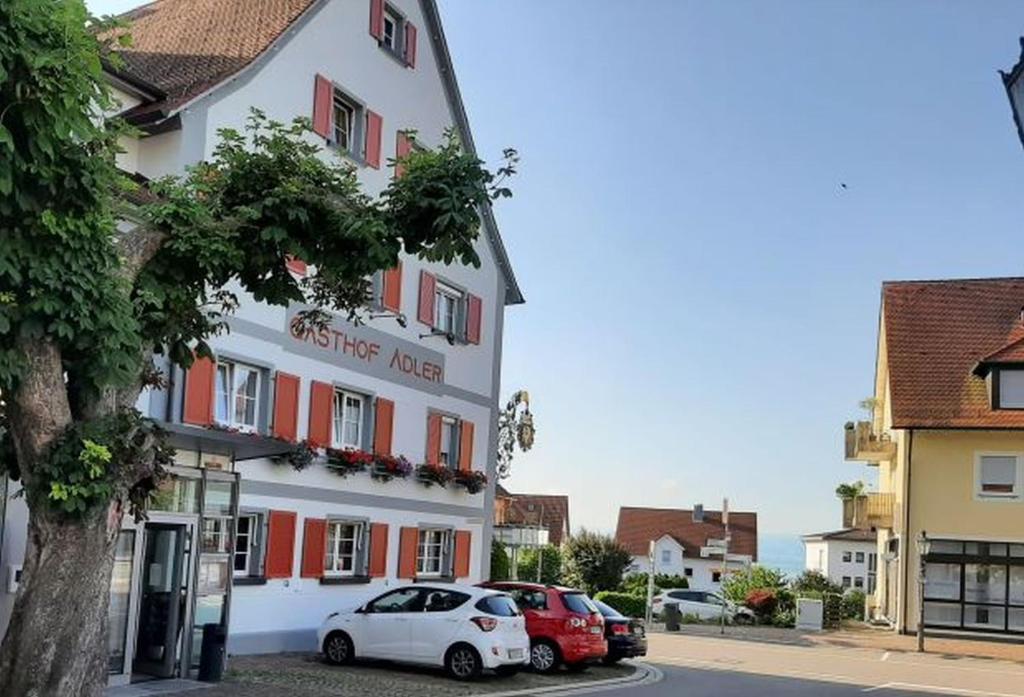 ein Gebäude mit zwei davor geparkt in der Unterkunft Hotel Restaurant Adler in Immenstaad am Bodensee