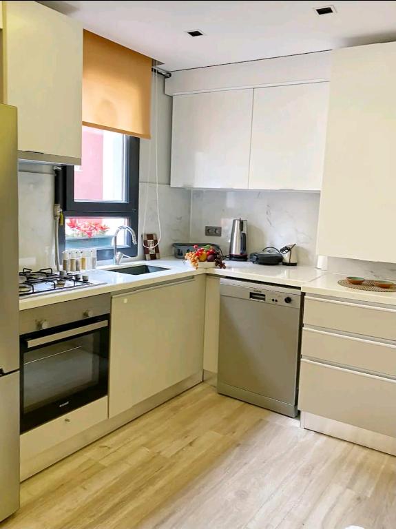 una cocina con armarios blancos y electrodomésticos de acero inoxidable en Şişli Merkez, en Estambul