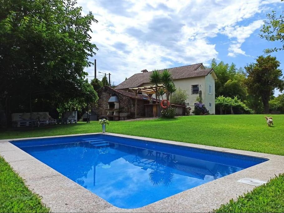 a blue swimming pool in front of a house at A Viña de Lina. Turismo rural con piscina y finca. in Pontevedra