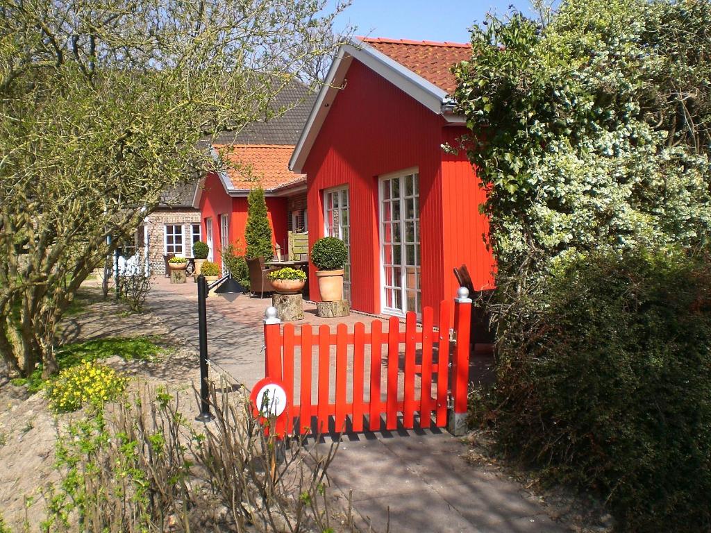 ein rotes Haus mit einem roten Zaun davor in der Unterkunft Katrins Ferienhof in Wüppels