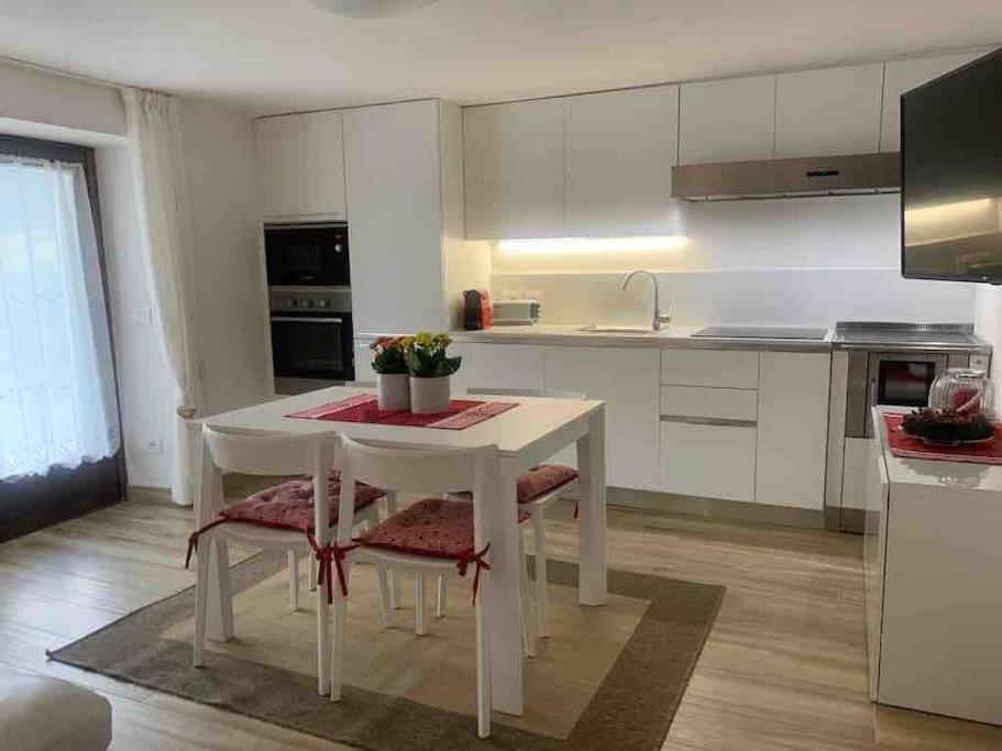 a white kitchen with a white table and chairs at Pinzolo, grazioso appartamento, wellness a 100 metri in Pinzolo