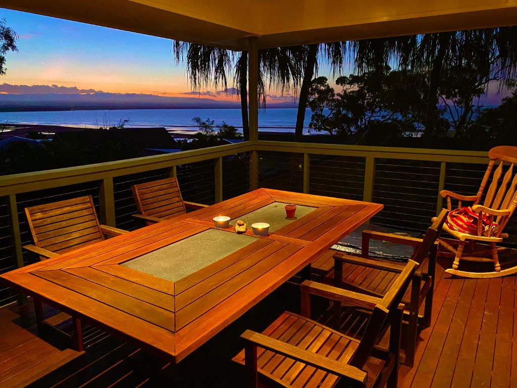 een houten tafel en stoelen op een terras met uitzicht op de oceaan bij Garreembee 1770 House in Seventeen Seventy