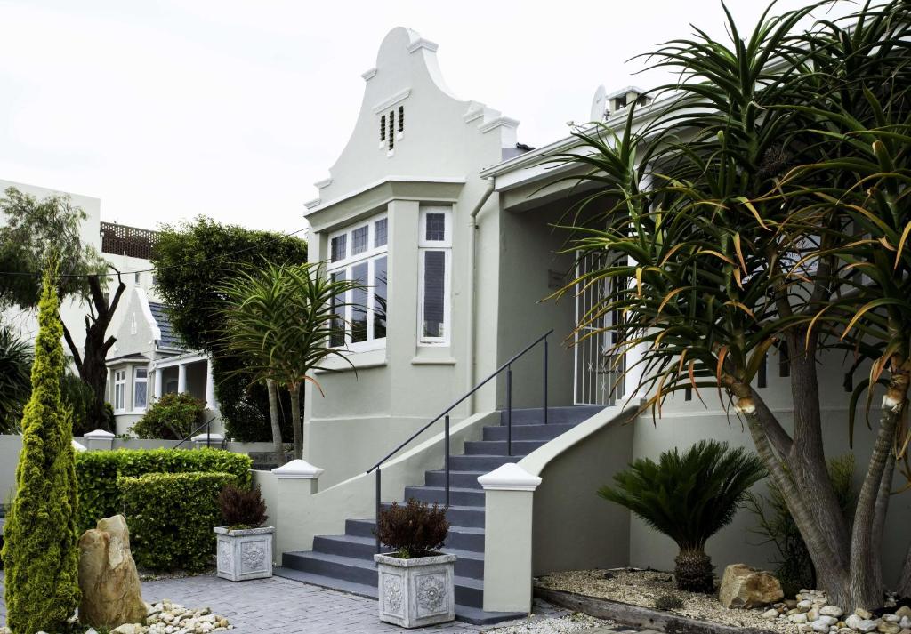 a white house with blue stairs and palm trees at Conifer Beach House in Port Elizabeth
