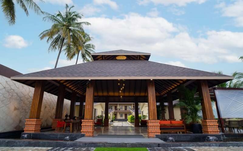 a gazebo with a palm tree and a building at Gandharv Resorts in Wai