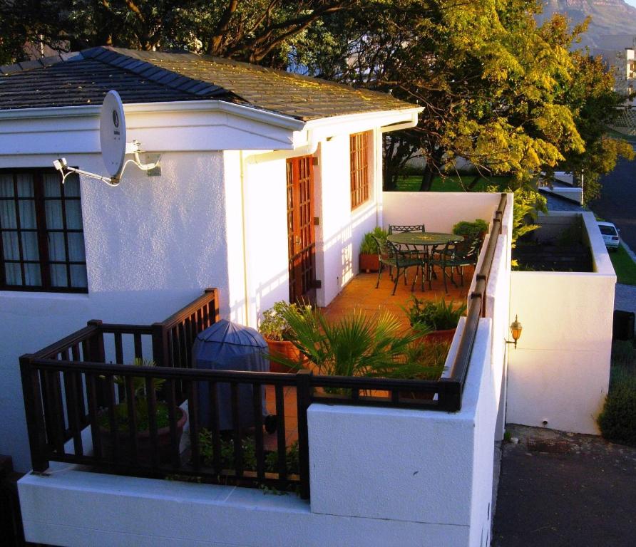 a small white house with a porch with a patio at Bakoven Cottage in Cape Town