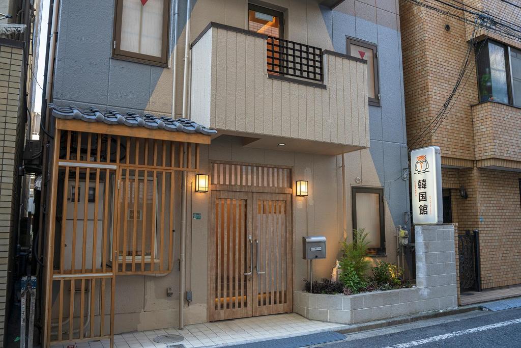 un edificio con puertas de madera en un lateral de una calle en ビジネスホテル韓国館, en Tokio