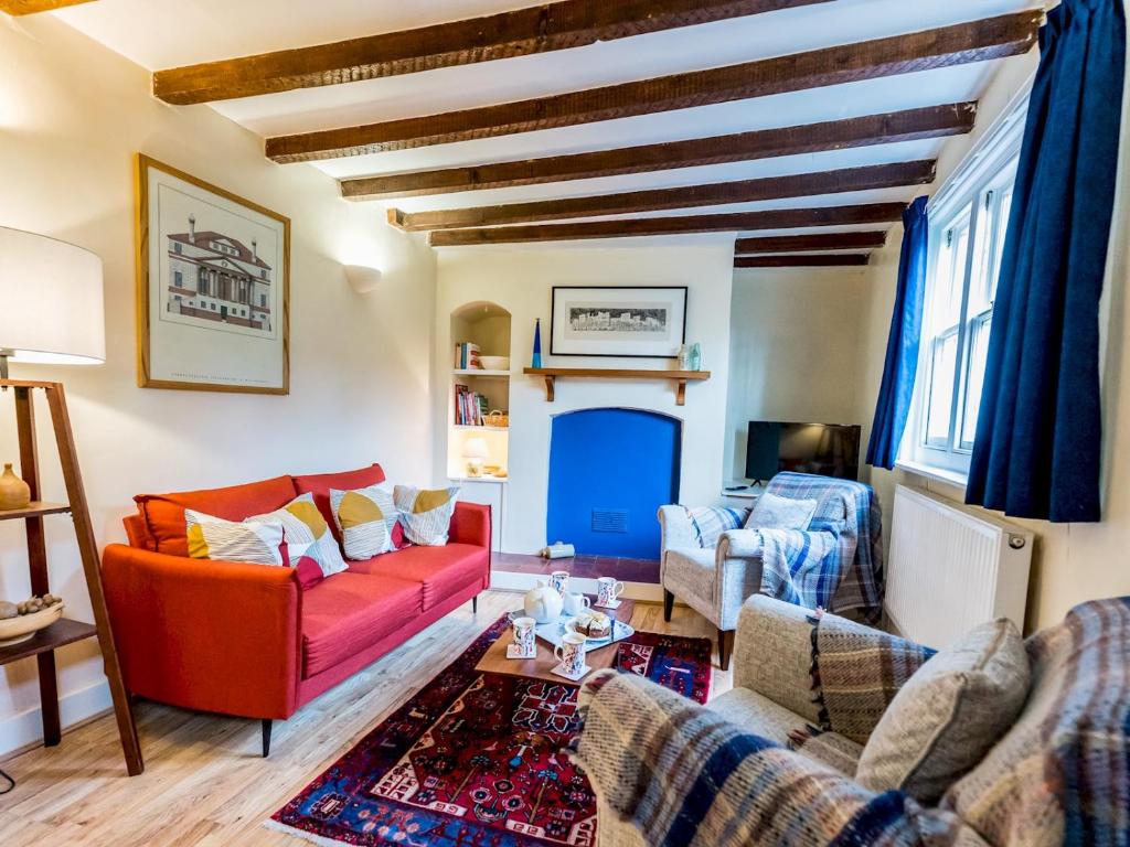 a living room with a red couch and a blue fireplace at Cosy 2 bedroom Victorian Cottage - Pass the Keys in Ludlow