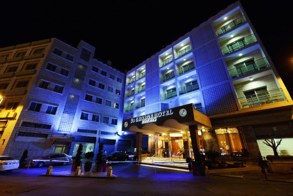 un edificio con luces azules por la noche en St. George Hotel, en Jerusalén
