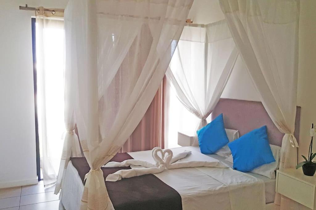 a bedroom with a white bed with blue pillows at Lovely 3-bedroom at Azuri Ocean & Golf village in Roches Noires