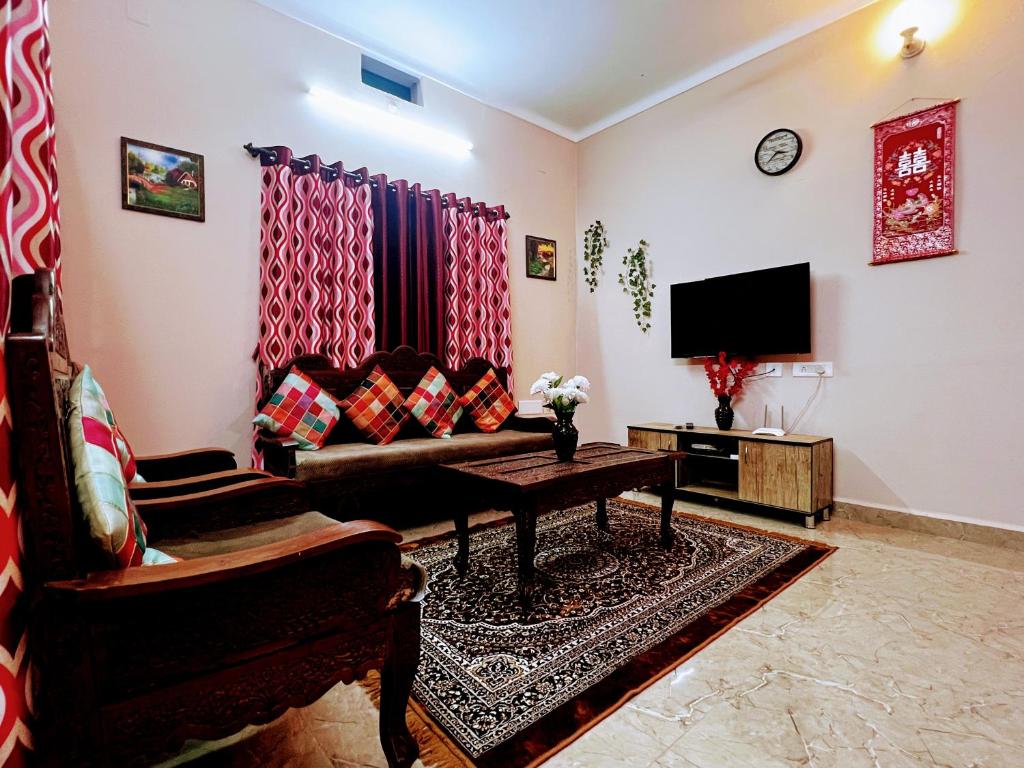 a living room with a couch and a tv at Peaceful villa amidst greenery within the city. in Manipal