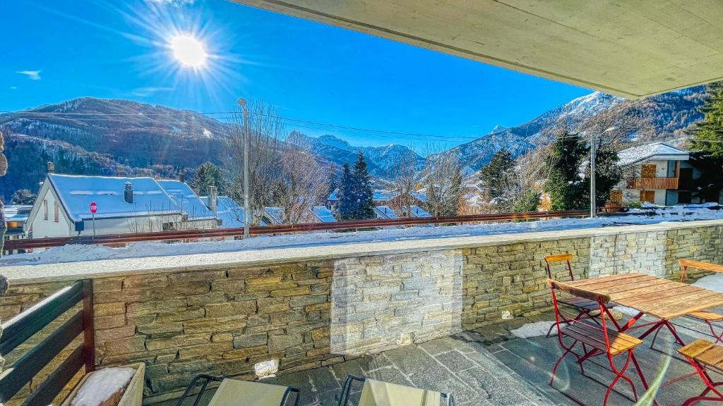 a balcony with a table and chairs and mountains at Appartamento La Sequoia - Affitti Brevi Italia in Bardonecchia