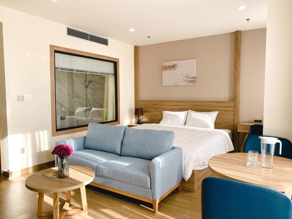 a hotel room with a bed and a couch and tables at PH Hotel & Apartment in Hai Phong