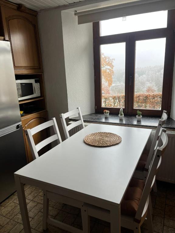 a white table and chairs in a kitchen with a window at Gîte Les trois charmes in Gouvy