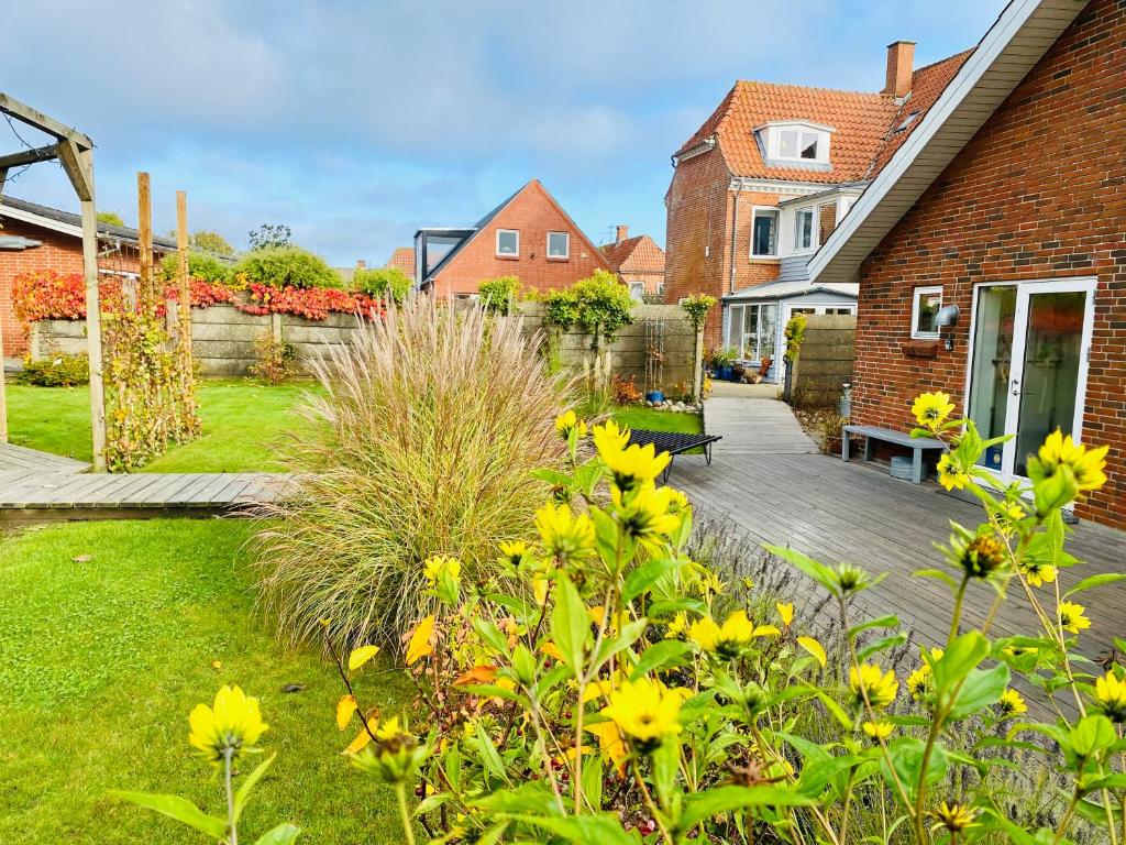 a garden with yellow flowers and a wooden deck at Event4U in Nykøbing Mors