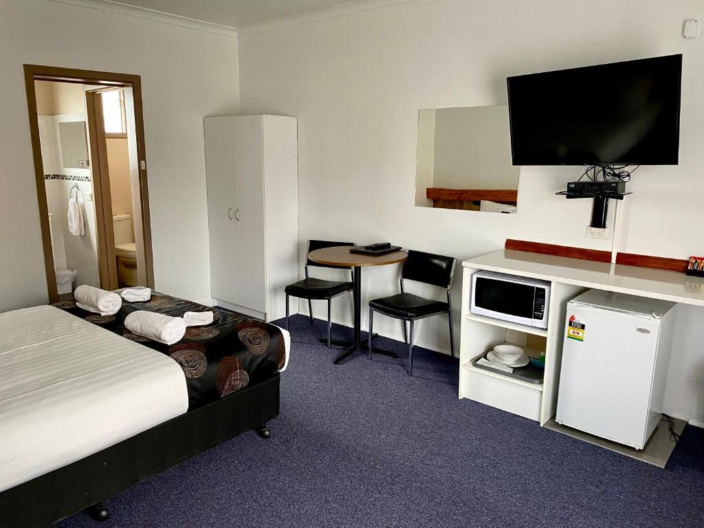 Habitación de hotel con cama y escritorio con TV. en Motel Stawell en Stawell