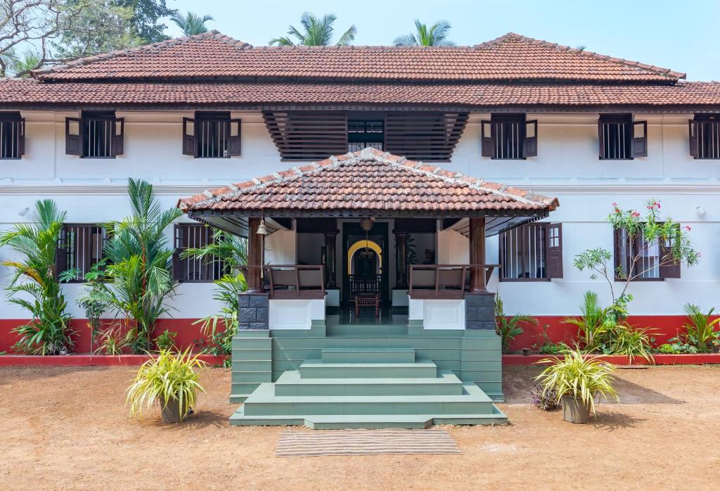 a house with a gate and stairs in front at SaffronStays Amaya, Kannur - 300 years old heritage estate for families and large groups in Kannur