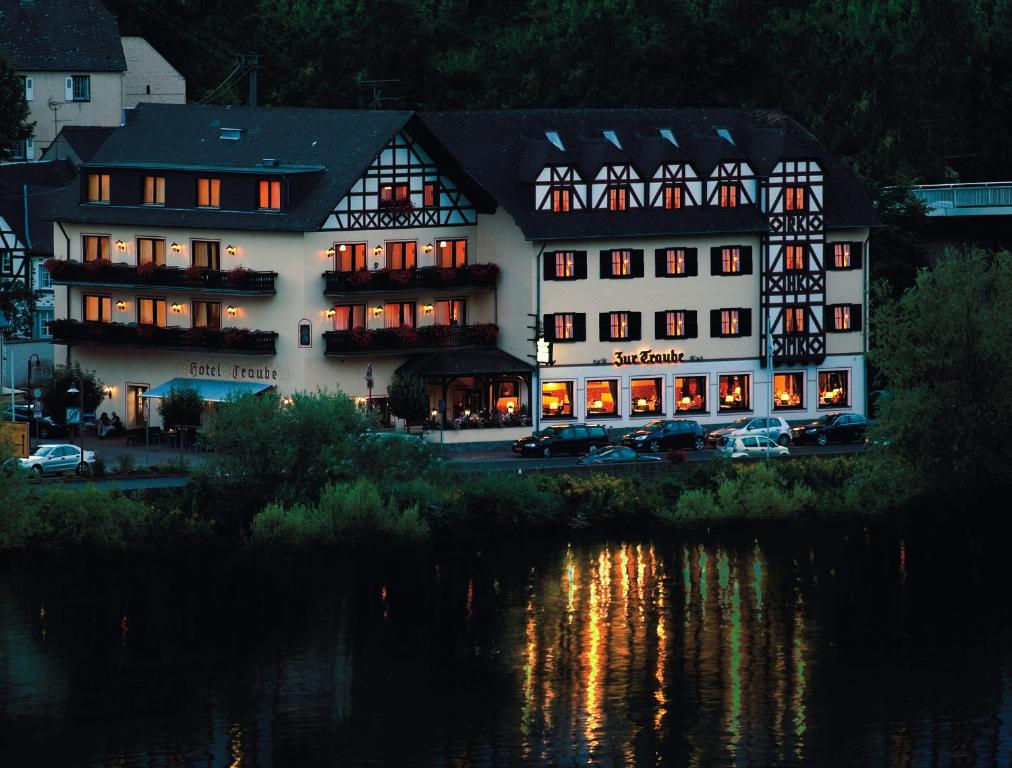 un gran edificio blanco junto a una masa de agua en Moselhotel & Restaurant Zur Traube GmbH, en Löf